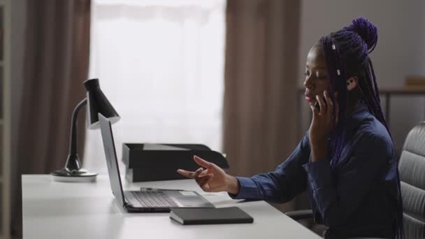 kobieta pracownik biurowy jest konsultantem klienta przez telefon komórkowy, siedzi przy stole z laptopem i rozmawia przez telefon komórkowy, portret - Materiał filmowy, wideo