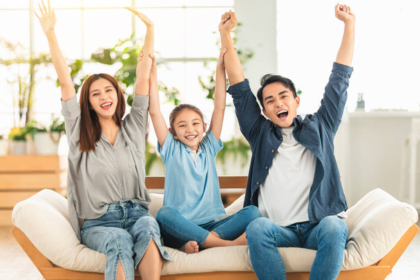  Familia feliz levantando las manos en el sofá en casa - Foto, Imagen