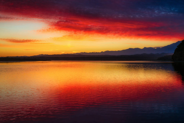 Дивовижний червоний і жовтий колір неба, що відбивається в Лагуні Окаріто на тлі Південних Альп на світанку. - Фото, зображення