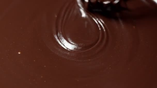 Mezclando, revolviendo el chocolate negro líquido derretido con batidor, el confitero prepara el postre, cubriendo - Metraje, vídeo