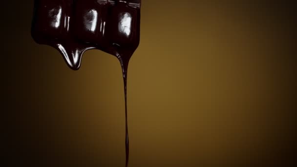 Chocolate bar with melted chocolate syrup dripping flowing over dark brown background, confectionery - Footage, Video