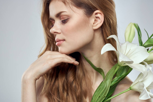 明るい背景に白い花を持つ美しい女性の肖像画 - 写真・画像