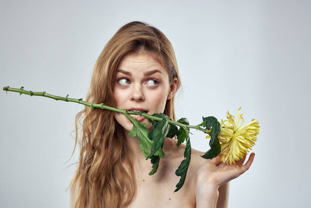Retrato de una hermosa mujer con una flor amarilla sobre un fondo claro recortado con Copy Space - Foto, imagen