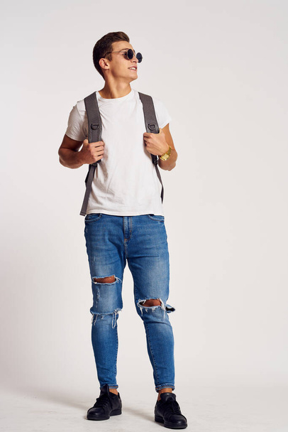 чоловік з рюкзаком на спині в джинсовій футболці кросівки та окуляри на обличчі
 - Фото, зображення