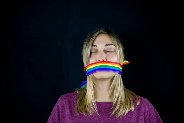 Conceptual image of censorship and social taboo on the LGBT community. Woman with lgbt tape wrapped around her mouth - Photo, Image