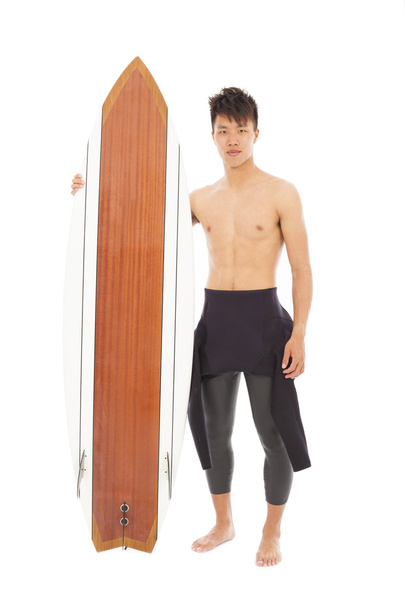 joven surfista usando traje de buceo y sosteniendo una tabla de surf
 - Foto, imagen