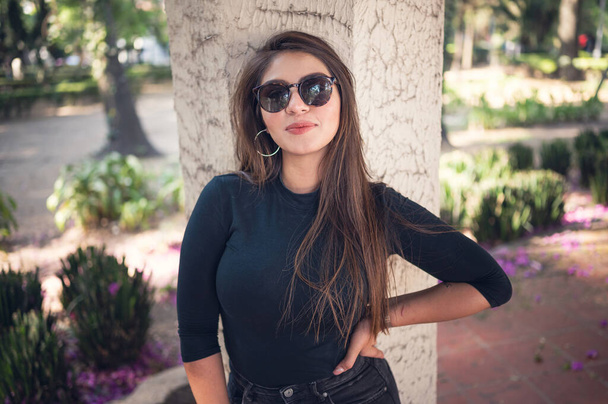 A cool sexy Mexican woman in sunglasses posing in a garden - Fotoğraf, Görsel