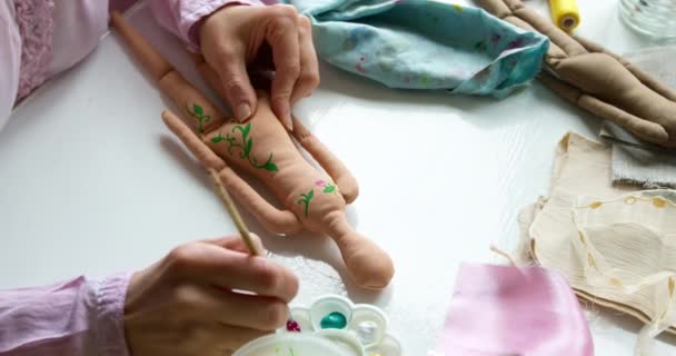 De meesterkunstenaar schilderde een handgemaakte textielpop. Naaldwerk. - Video