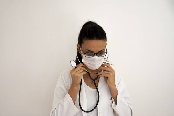 La giovane dottoressa con gli occhiali indossa uno stetoscopio. Mi preparo per la giornata. Focus selettivo Mano e viso. - Foto, immagini