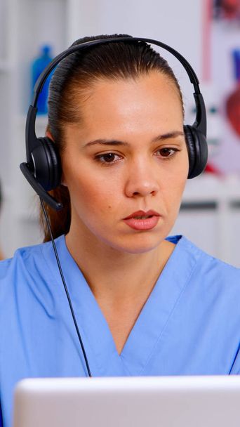 Asistent lékaře pomocí sluchátek v nemocnici odpovídá na volání pacientů - Fotografie, Obrázek