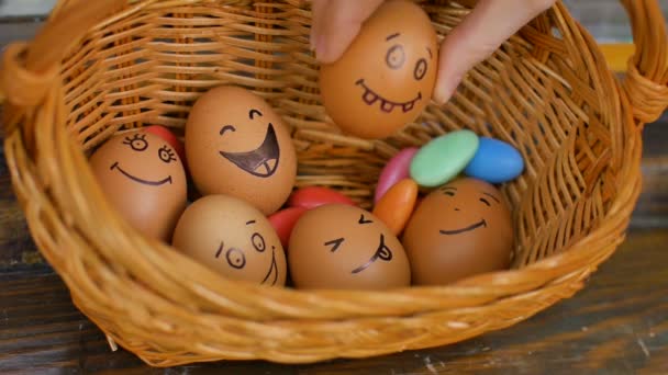 Stapel handgezeichneter Smiley-Eier auf Strohkorb mit bunten Bonbons, Ostervorbereitung, Konzepte für Feiertagsstimmung - Filmmaterial, Video