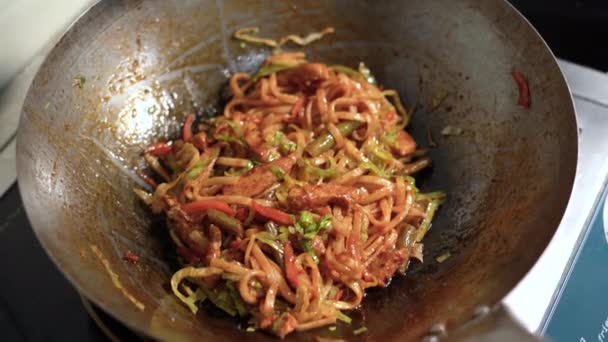 Close-up van noedels in een wok gestoofd in olijfolie. - Video