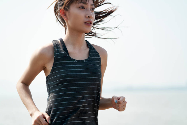 młoda Azjatka kobieta jogger działa nad morzem - Zdjęcie, obraz