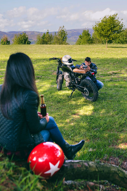 Ζευγάρι ξεκουράζεται από ένα ταξίδι με μοτοσικλέτα λήψη φωτογραφιών - Φωτογραφία, εικόνα