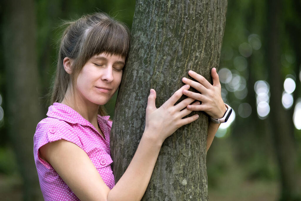 Jovem mulher feliz abraçando grande tronco de árvore no parque de verão. - Foto, Imagem