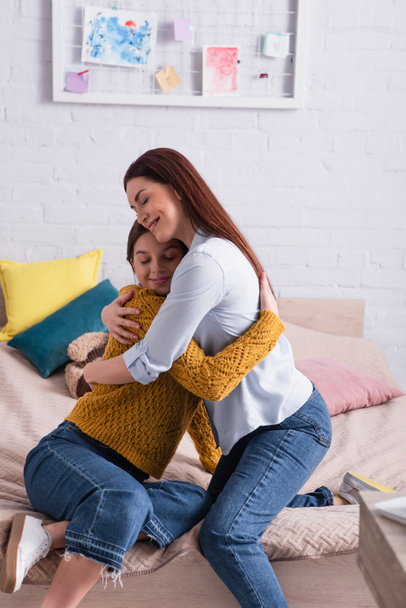 Mutter und Tochter im Teenageralter umarmen sich im Schlafzimmer - Foto, Bild