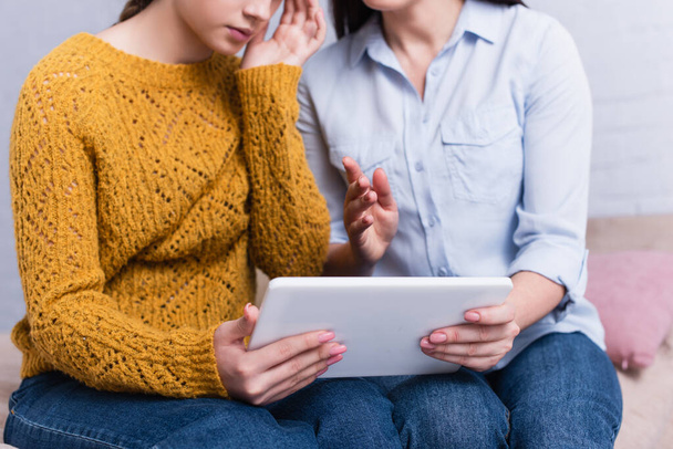 partial view of teenage girl and mother holding digital tablet - Photo, Image