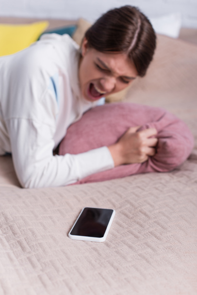 verschwommenes Teenager-Mädchen schreit nahe Smartphone mit leerem Bildschirm - Foto, Bild
