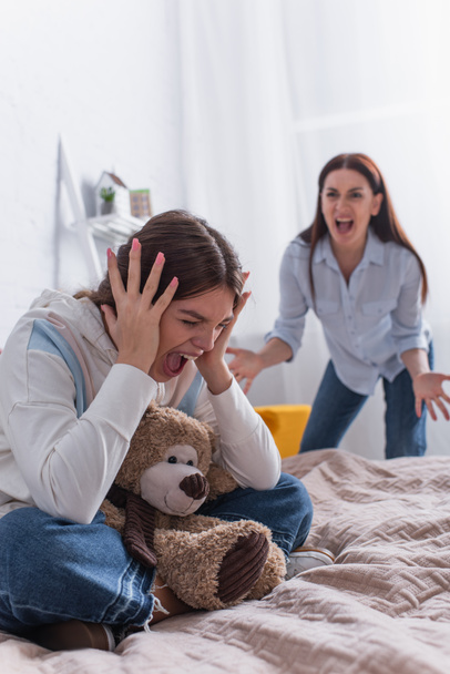 teenage girl screaming near angry mother on blurred background  - Photo, Image