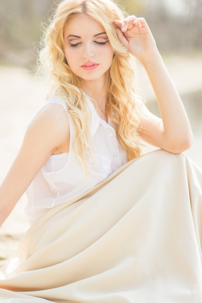 Portrait of a beautiful young blonde woman with wavy hair in nature - Fotoğraf, Görsel
