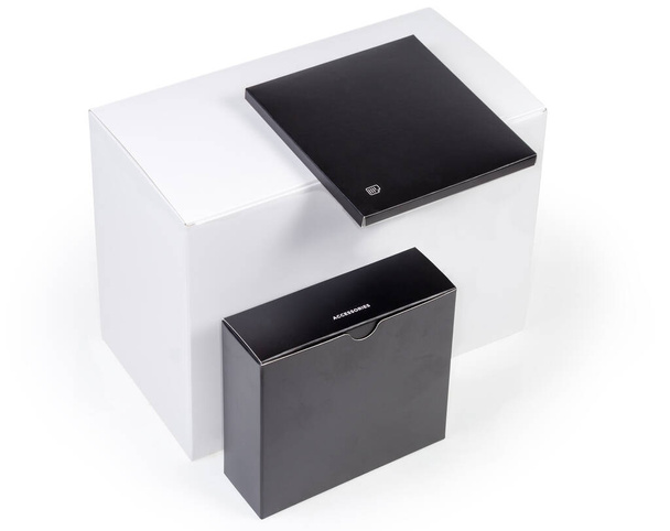Scatola di imballaggio rettangolare bianca grande chiusa e due piccole scatole piatte nere con accessori e manuale con marcatura corrispondente  - Foto, immagini