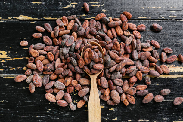 Ложка с бобами какао на темном деревянном фоне - Фото, изображение
