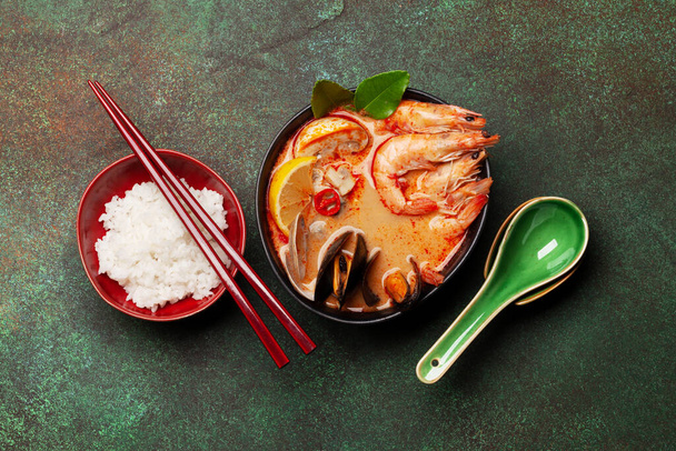 Soupe traditionnelle thaïlandaise Tom Yum kung avec fruits de mer, lait de coco et piment et bol de riz. Vue du dessus plat lay - Photo, image