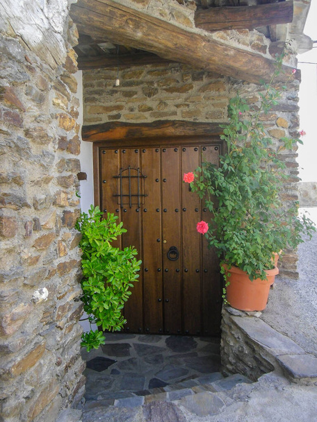 brwon fa bejárati ajtó fém ajtó kopogtató kő fal és növények Spanyolországban - Fotó, kép