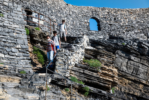 Porto Venere, Ligurie, Italie. Juin 2020. L'escalier qui vous permet de descendre dans le golfe des Poètes avec la célèbre grotte de Lord Byron, poète et diplomate anglais. Une femme d'âge moyen et deux garçons - Photo, image