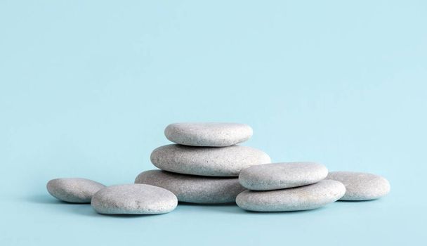 Concepto de fondo minimalista de productos de belleza. Piedras de mar planas de color gris apiladas como un pedestal mucho espacio de copia sobre fondo azul. - Foto, imagen