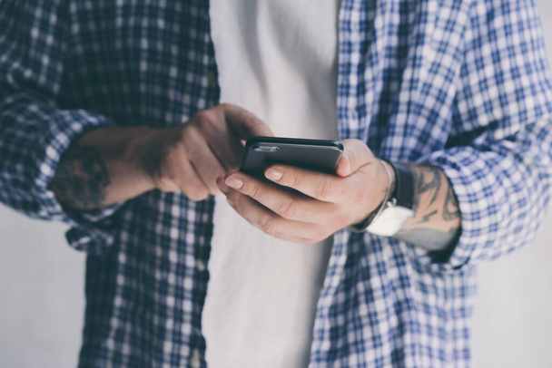 Young man pointing on smartphone screen, chatting in social networks, meeting website, searching internet, sending sms, using text messenger or online banking. Close up of male hands with mobile - Photo, Image