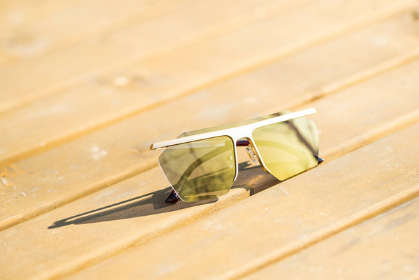 Φουτουριστικό Υπερμεγέθη γυαλιά ηλίου μοντέλο με χρυσούς φακούς πυροβολούν έξω σε ένα κοντινό πλάνο καλοκαιρινής ημέρας. Επιλεκτική εστίαση - Φωτογραφία, εικόνα