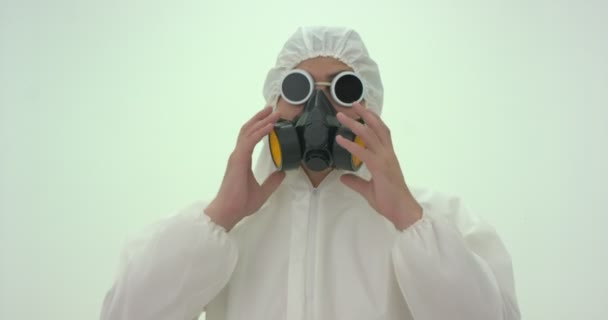 白い化学保護スーツの男の閉鎖とガスマスクの低下は、右上に彼の頭の上に電源を入れ、彼のマスクを置く。しばらくするとまたマスクを下げて - 映像、動画