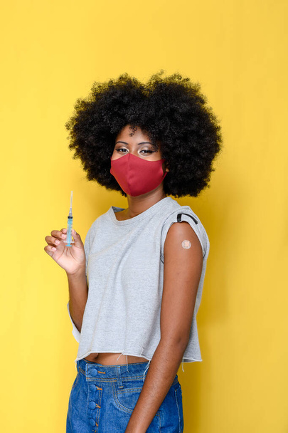 menina afro adolescente segurando seringa mostrando que ela foi vacinada durante a imunização contra o coronavírus covid-19 - Foto, Imagem