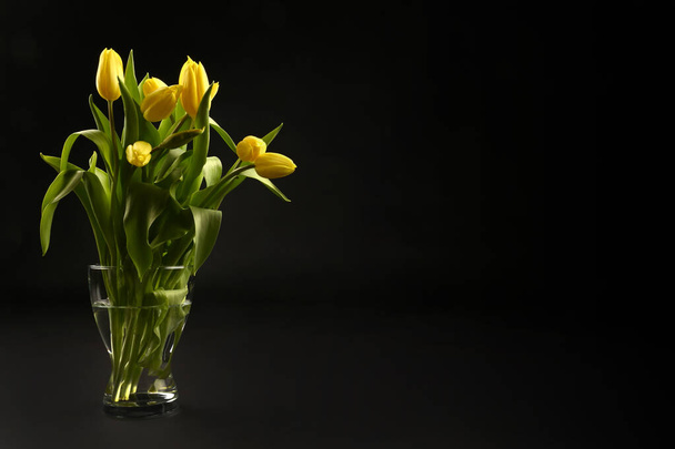Sárga tulipán fekete háttér, felső nézet, tavaszi csokor egy vázában - Fotó, kép