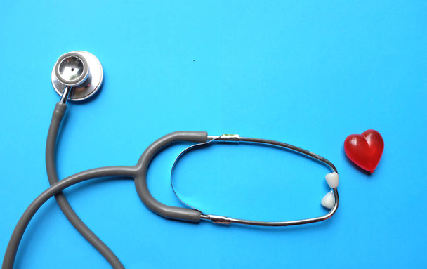 widok z góry Stetoskop i czerwone serce na niebieskim stole lekarskim.koncepcja gabinetu lekarskiego - Zdjęcie, obraz