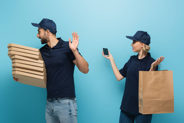 arabian delivery man showing refuse gesture near courier holding smartphone on blue - Photo, Image
