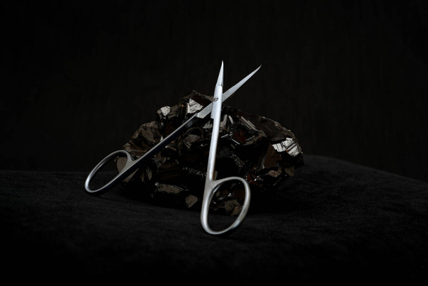 nail scissors on a stone on a black background                - Photo, Image