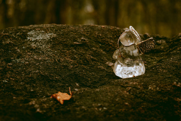 ラトビアのドベレ近くの神秘的なポカニの森の石の上に小さなガラスの天使の場所 - 写真・画像