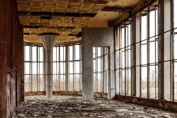 Разрушенный зал старого здания с широкими окнами. Разбитое стекло на полу. - Фото, изображение