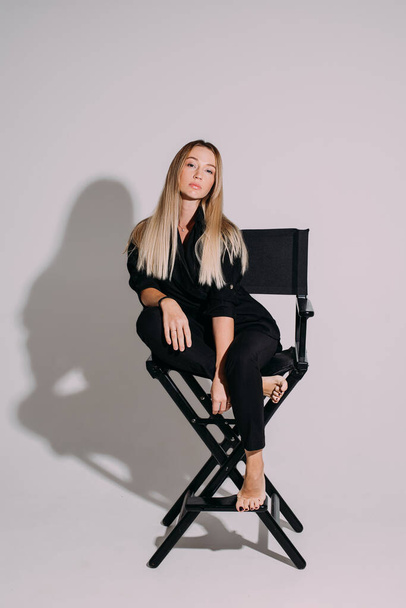 Trendy magabiztos modell teljes fekete rendezői szék. - Fotó, kép