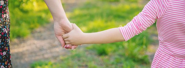 Egy gyerek az anyjával kéz a kézben jár. Szelektív fókusz. természet. - Fotó, kép