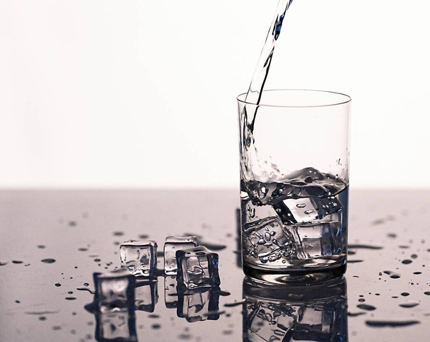 pulverización de agua clara en un vaso con hielo, agua clara en un vaso con pulverización de cerca - Foto, Imagen