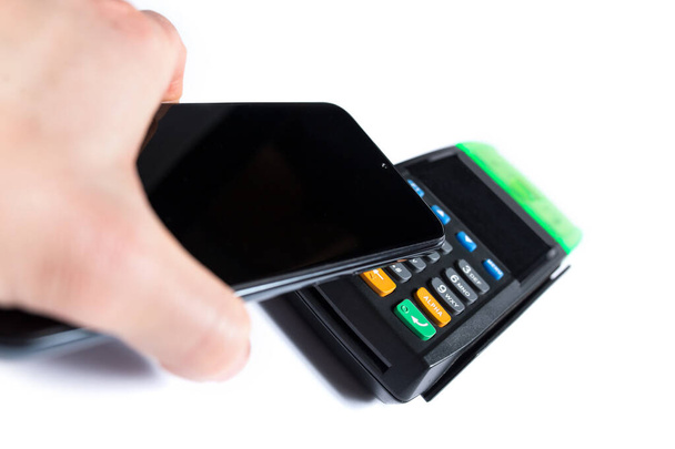 Hand paying with smartphone on contactless terminal isoalted on a white background. - Foto, Imagem
