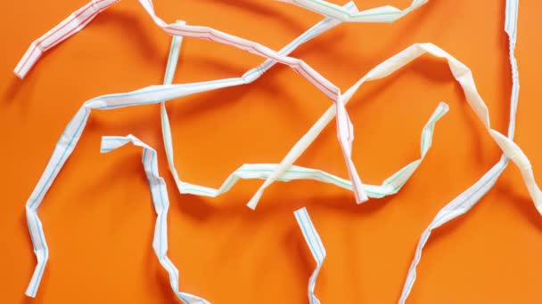 Used plastic drinking straws on the orange background top view - Footage, Video