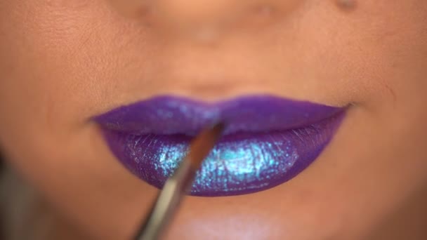 vista parziale della donna che applica lucidalabbra con luccichio sulle labbra viola  - Filmati, video