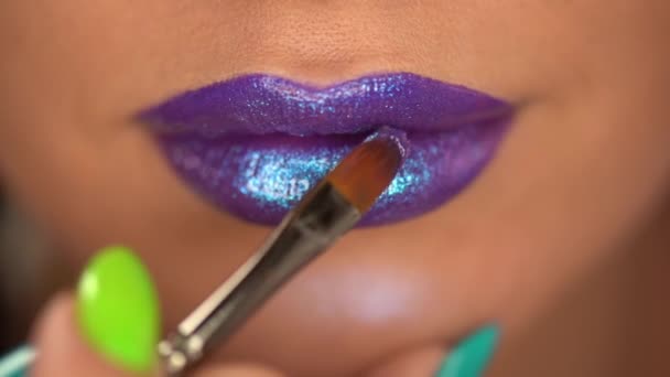 cropped view of woman applying sparkling lip gloss with shimmer on purple lips  - Video