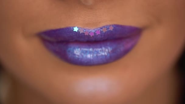 rack focus de la femme avec des étoiles sur les lèvres violettes avec chatoiement - Séquence, vidéo