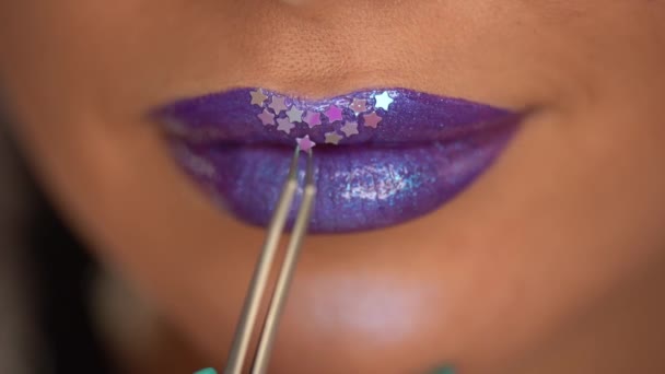 cropped view of woman applying star with tweezers on purple shiny lips - Video