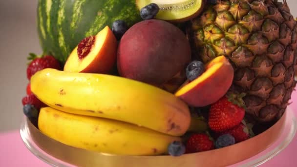 primer plano de varios de deliciosas frutas y bayas en soporte de pastel - Imágenes, Vídeo